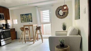A modern living room with a sofa, a coffee table, and a dining area with chairs. - 1 bedroom with pool in Simpson Bay - GENERATOR (1-3B) (Simpson Bay)