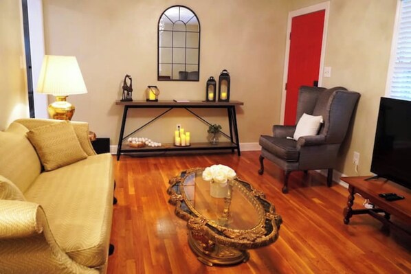 Una sala de estar con sofá, sillón, mesa de centro y televisor.