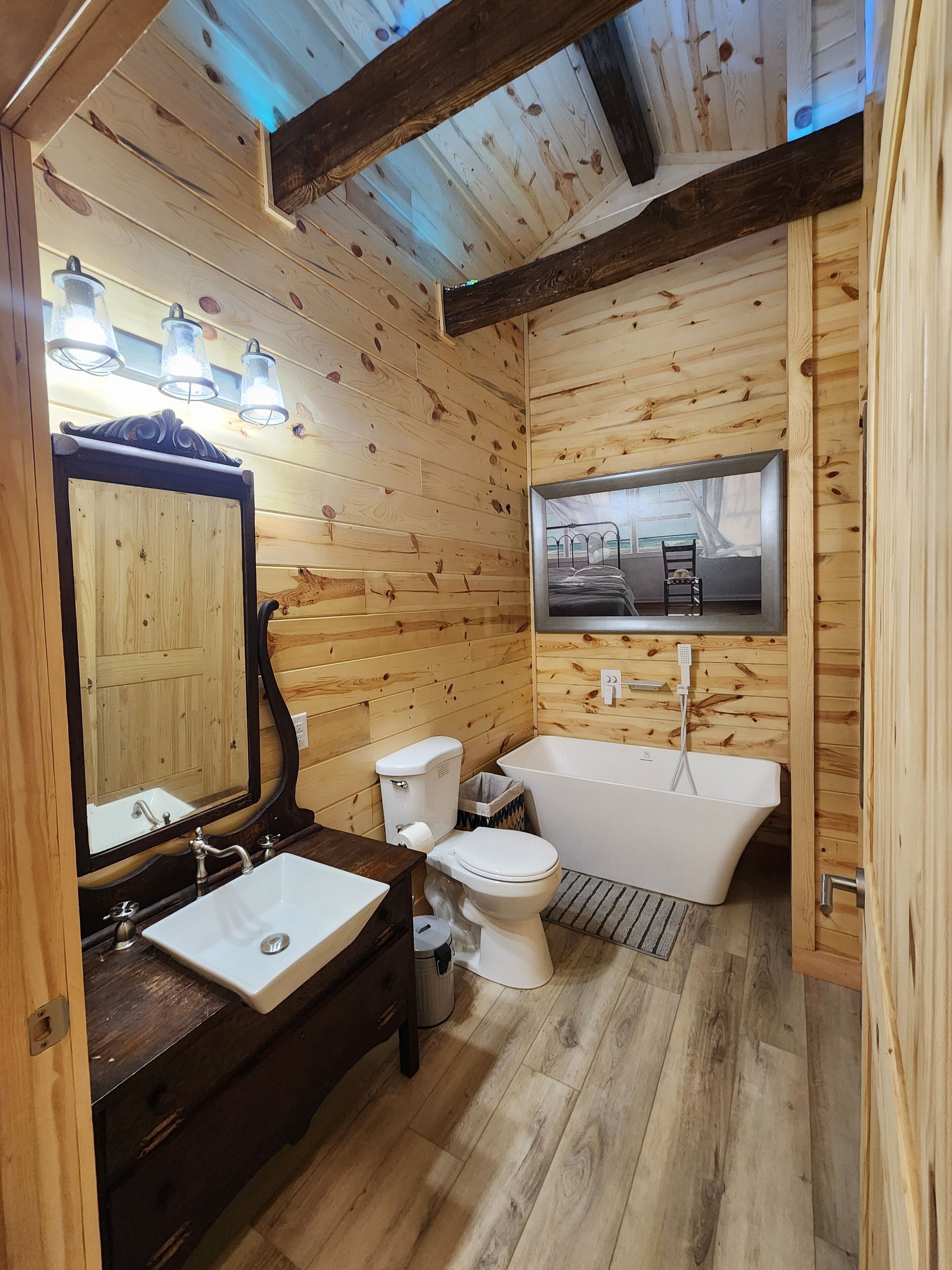 A wooden cabin bathroom with a sink, toilet, and bathtub.