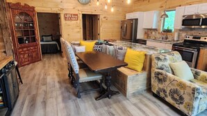 L’intérieur d’un chalet en bois chaleureux et accueillant, avec un coin repas, un canapé et une cuisine.