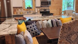 Une cuisine chaleureuse, aménagée dans le style d’un chalet, avec des murs en bois, un plan de travail en marbre et un four encastré.