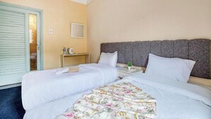 A hotel room with two beds, a small bedside table with a lamp, a mirror, and a door with a frosted glass panel. - Deluxe Double or Twin Room with Pyramids View (Giza Governorate)