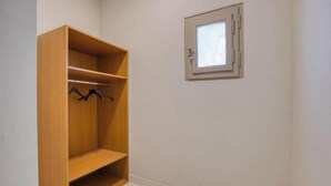 Une pièce avec une armoire en bois, une petite fenêtre et un sol carrelé.