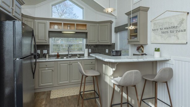 A kitchen with a large island, bar stools, and a window with blinds.