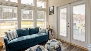 A cozy room with a blue sofa, a small side table, and a large window with blinds.
