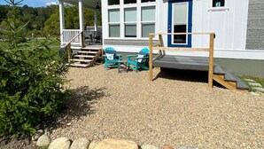 A two-story house with a porch, a blue door, and a small deck.