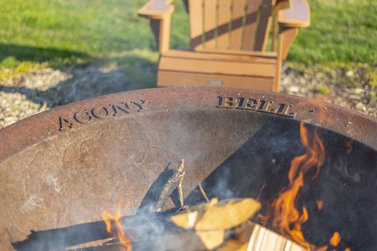 A metal fire pit with inscriptions and a burning log.