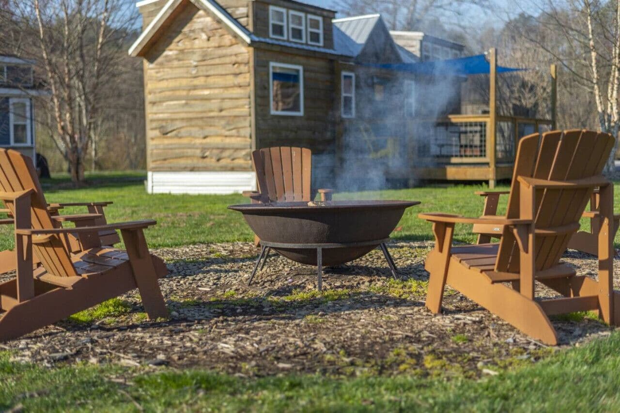Een rustieke blokhut met een houtkachel en Adirondack-stoelen op de voorgrond.