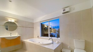 Ein modernes Badezimmer mit einer freistehenden Badewanne, einer Toilette und einem Fenster mit Ausblick.