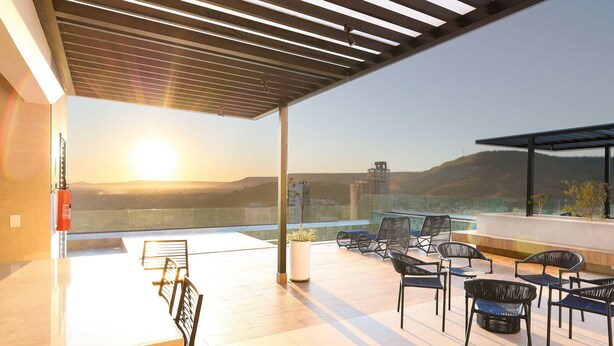 A rooftop terrace with a dining area, outdoor seating, and a view of the cityscape. - City House (Barreiras)