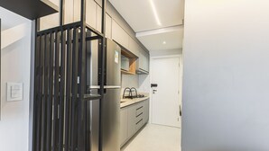 A modern kitchen with stainless steel appliances, grey cabinets, and a white door. - City House (Barreiras)