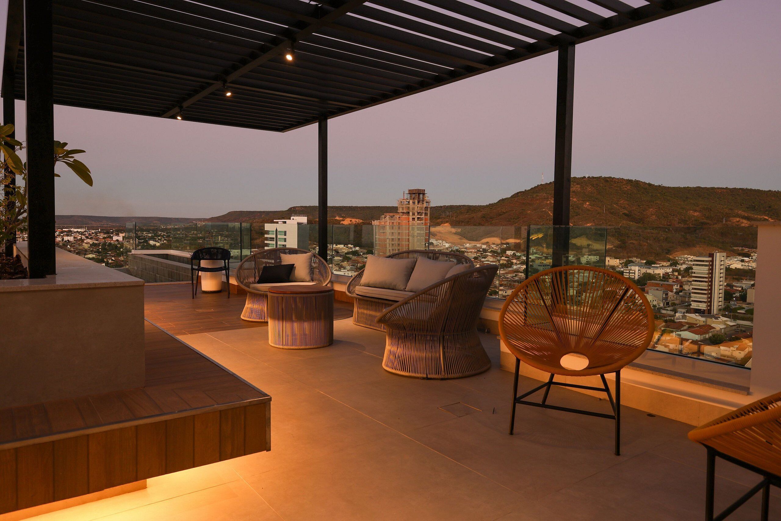 Une terrasse sur le toit offrant une vue sur le paysage urbain, avec un espace salon comprenant des fauteuils en osier et une table ronde.