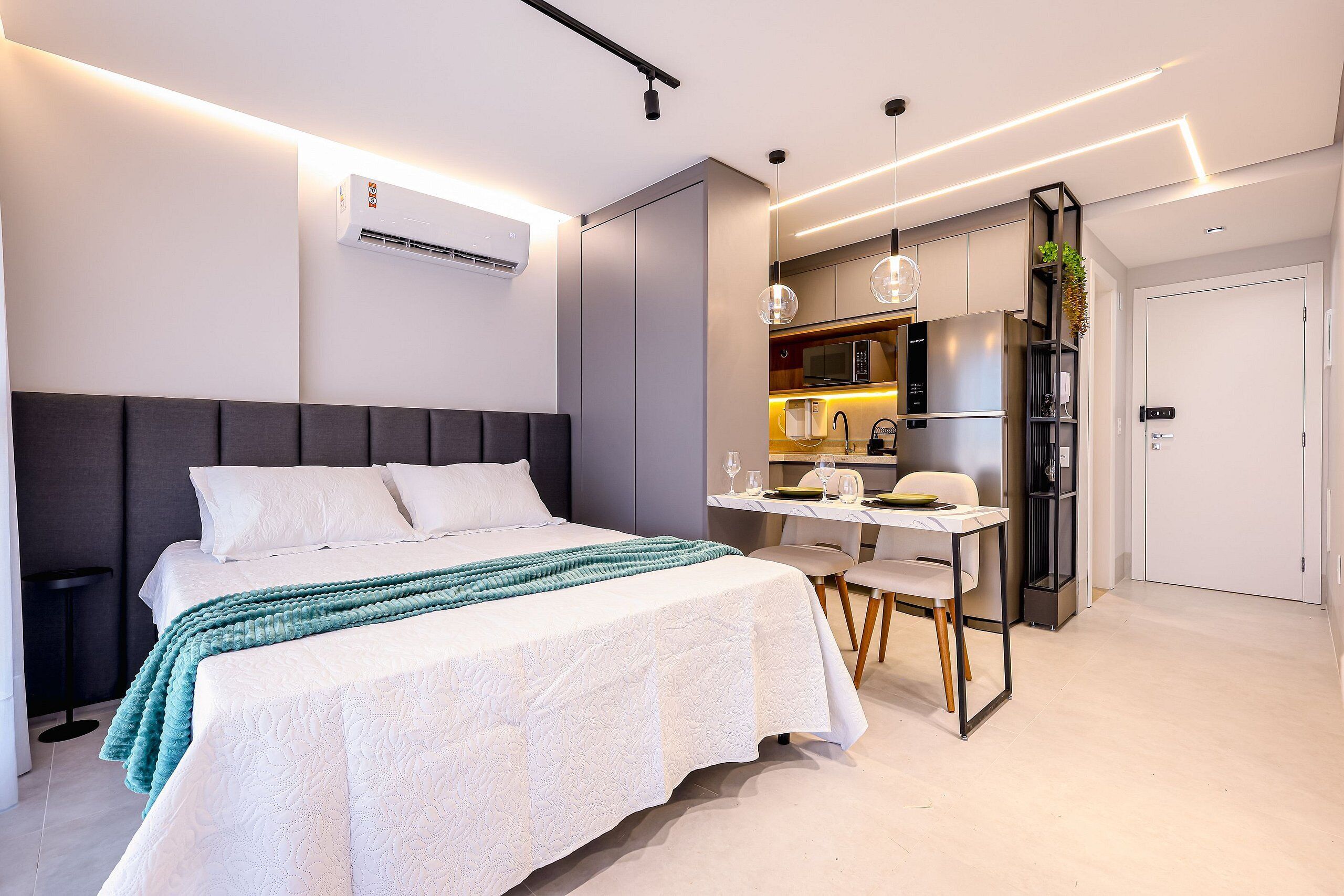 Ein modernes Schlafzimmer mit einem großen Bett, einem Schreibtisch und einer Küchenzeile.