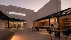 CITY HOUSE with a modern architectural design, featuring a spacious outdoor seating area with chairs and tables, and a well-lit entrance. - City House (Barreiras)