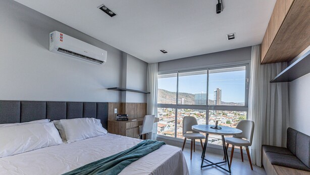 A hotel room with a bed, a round table, two chairs, a sofa, and a large window with a city view. - City House (Barreiras)