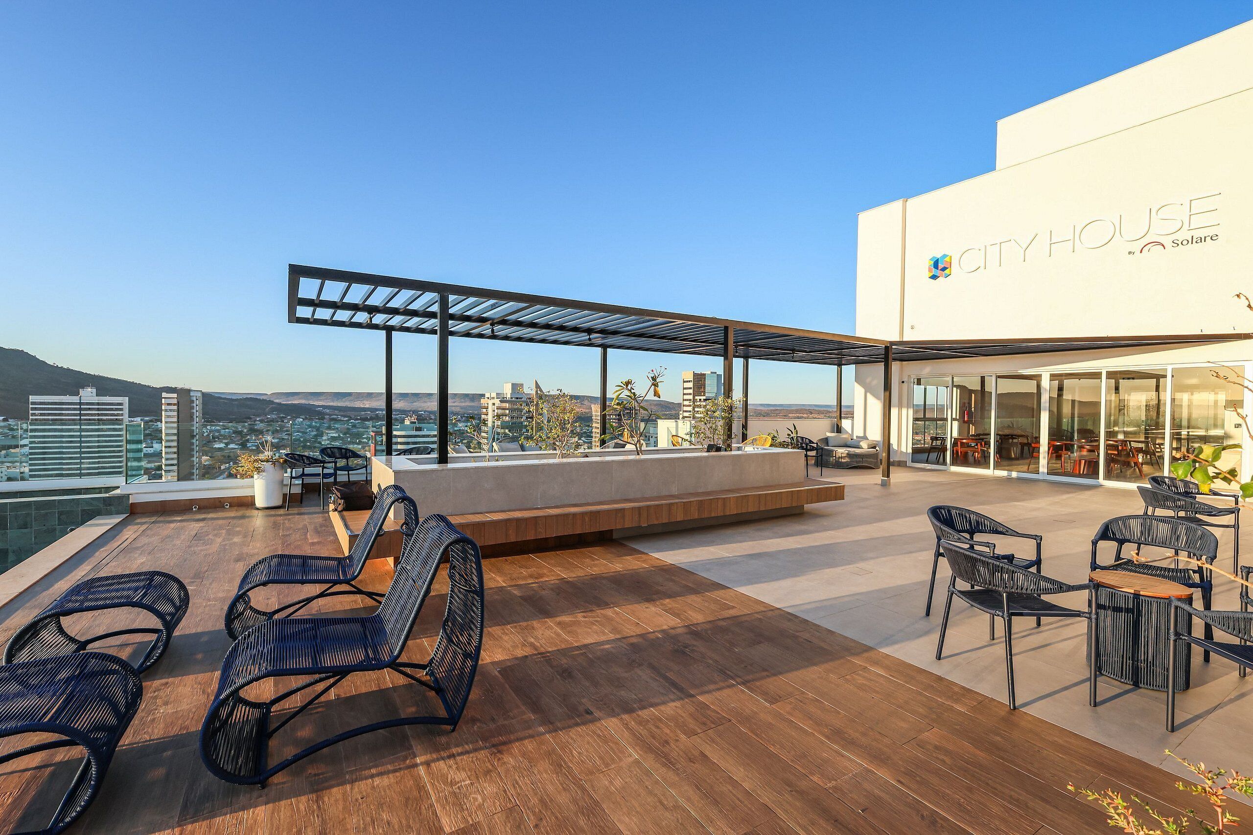 A rooftop terrace with outdoor seating, a pergola, and a view of the city skyline.