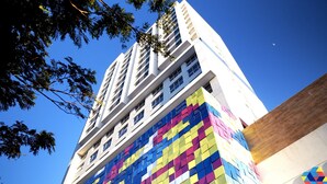 A high-rise building with a colorful facade and a clear blue sky in the background. - City House (Barreiras)