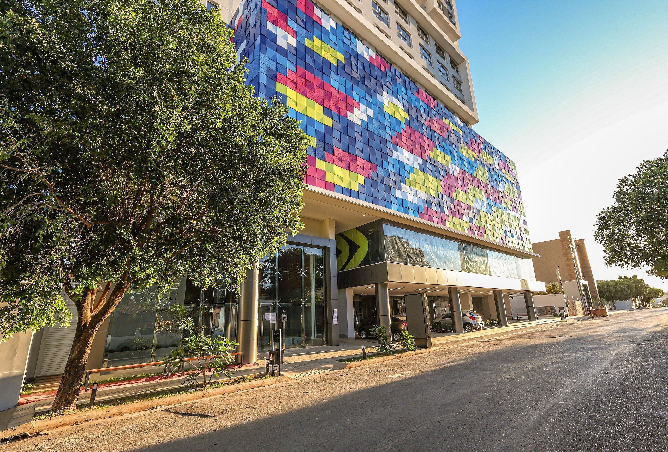A modern building with a colorful facade, large windows, and a covered entrance area.