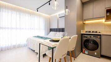 A modern bedroom with a bed, bedside table, and a washing machine in the corner.