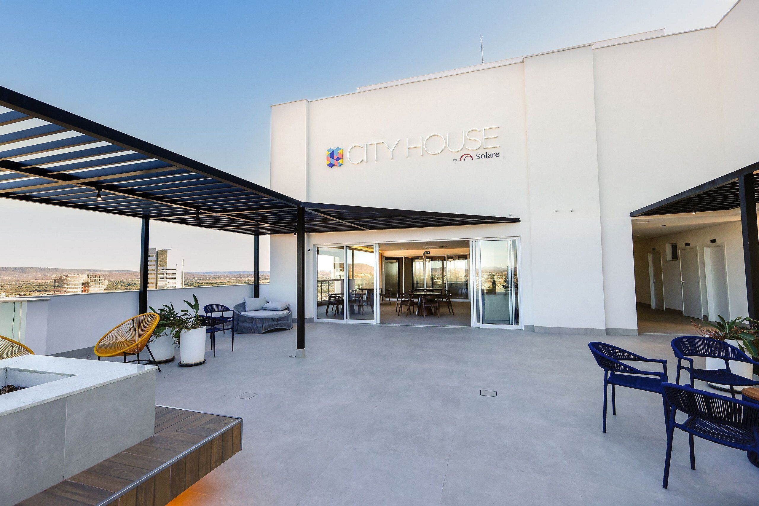 A modern building with a sign reading "CITYHOUSE by Solare." It features an outdoor patio with seating and a fire pit.