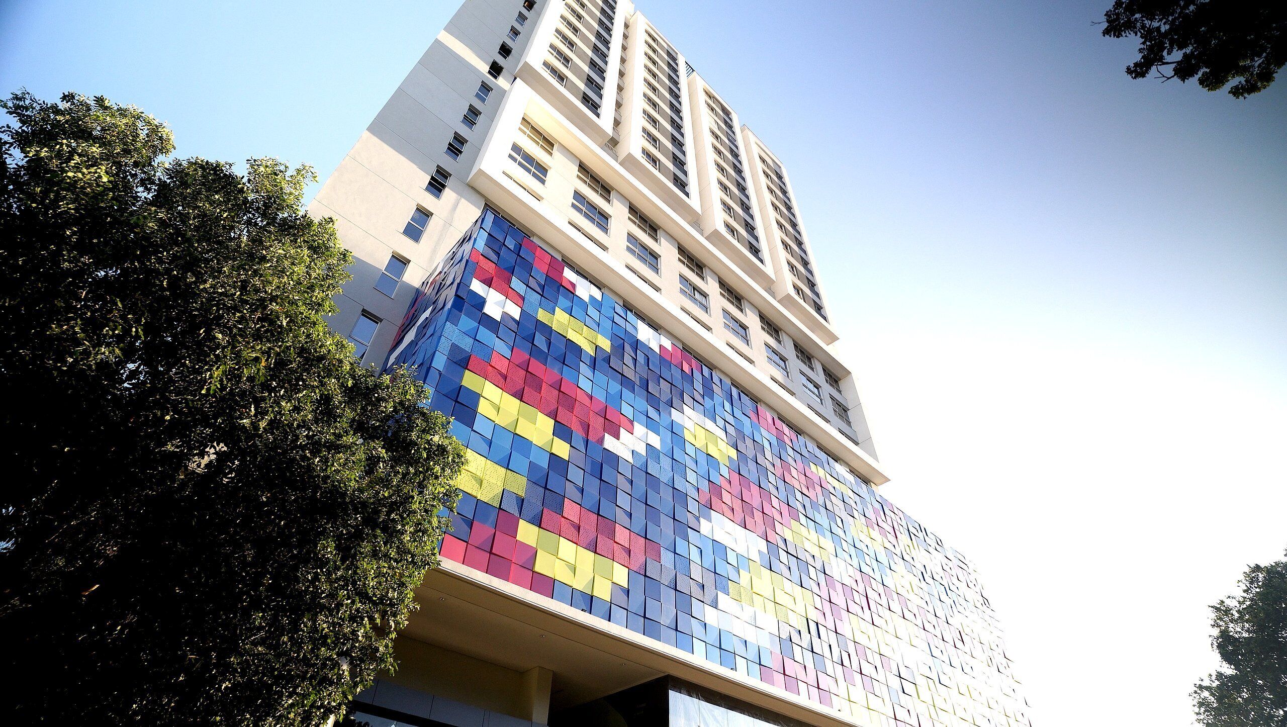 A tall building with a colorful mosaic facade and a clear sky.