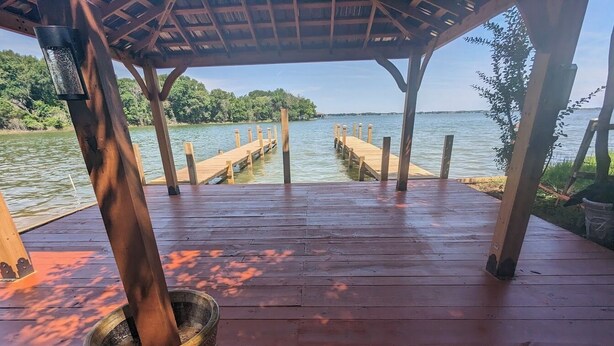 A wooden deck with a view of a lake and dock. - 1-bedroom/bath Cozy rustic cottage, off the RCR with AC in lovely Wrinkler, Tx.  (Streetman)
