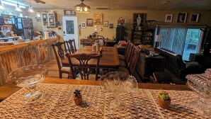 A cozy restaurant with a wooden dining area, a bar with a counter, and a television in the background. - 1-bedroom/bath Cozy rustic cottage, off the RCR with AC in lovely Wrinkler, Tx.  (Streetman)