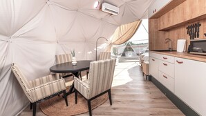 A tented outdoor kitchen with a dining table and chairs, a microwave, and a sink.