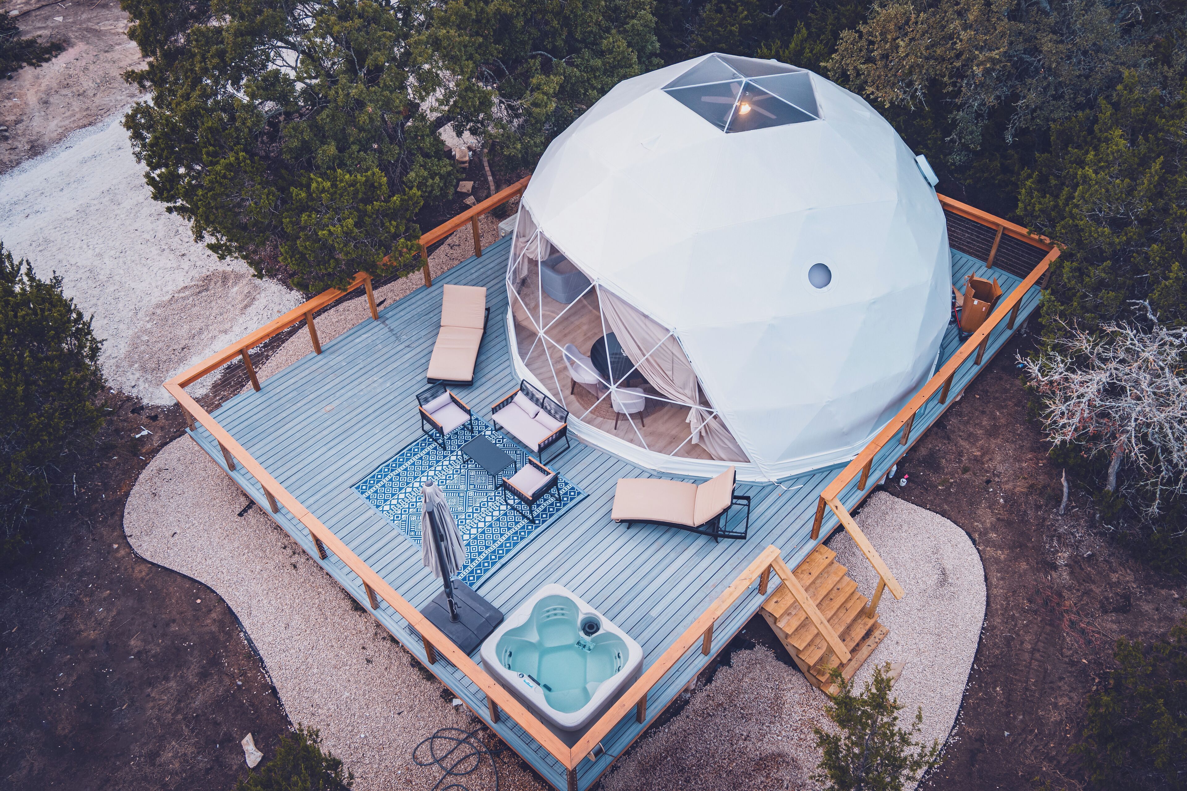 Een koepelvormige constructie met een terras, zitplaatsen buiten en een jacuzzi.