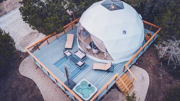Een koepelvormige constructie met een terras, zitplaatsen buiten en een jacuzzi.