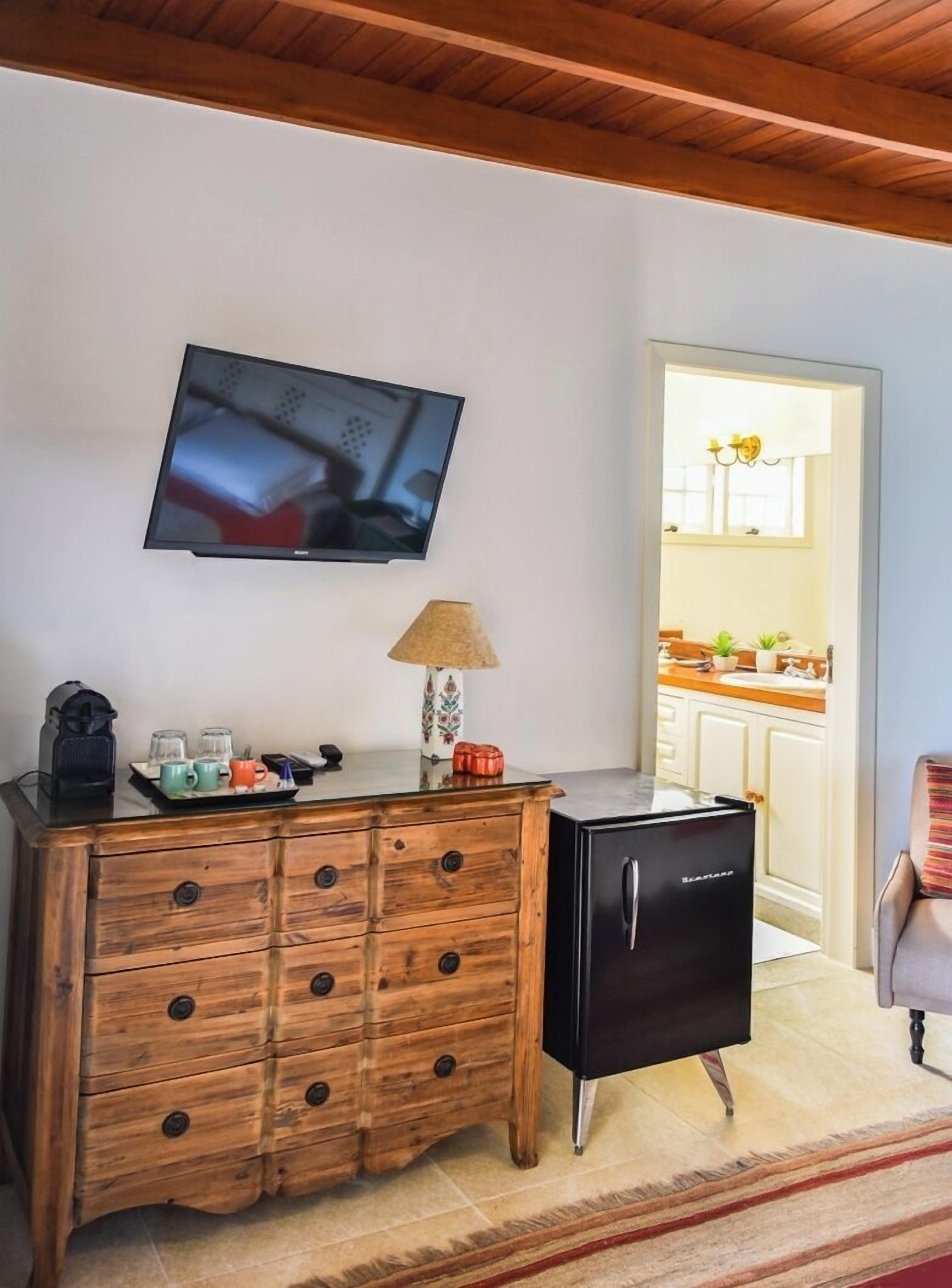 A living area with a wooden cabinet, a television, and a small refrigerator.