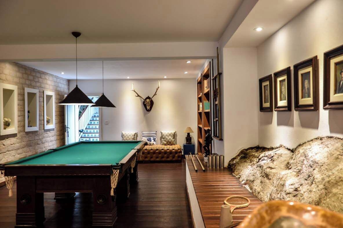 A billiards room with a pool table, a leather sofa, and a mounted deer head.