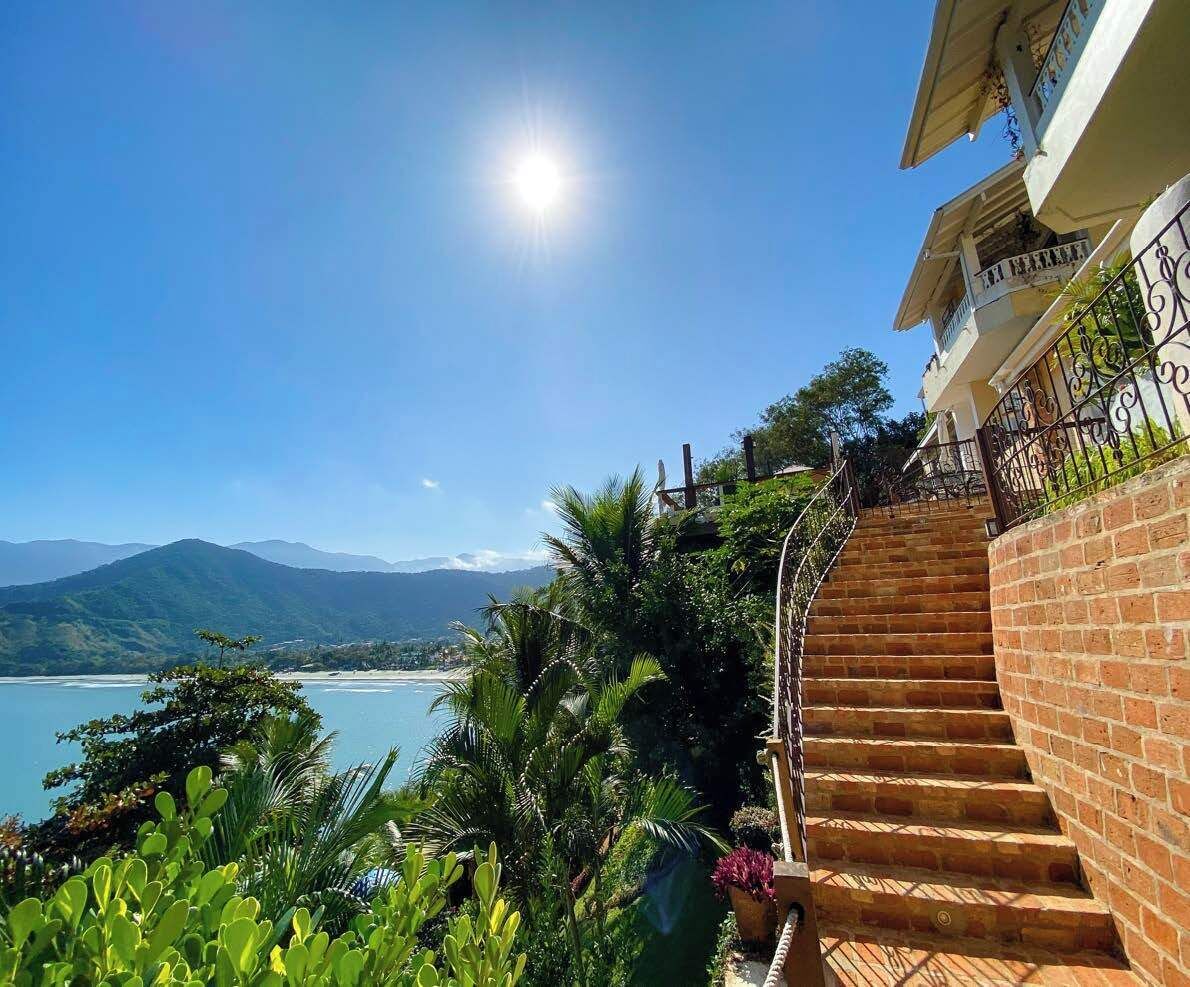 Una escalera conduce a un balcón con vistas a un paisaje costero y montañas a lo lejos.