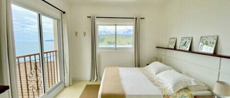Un dormitorio con cama, mesita de noche, ventana con vistas y balcón.