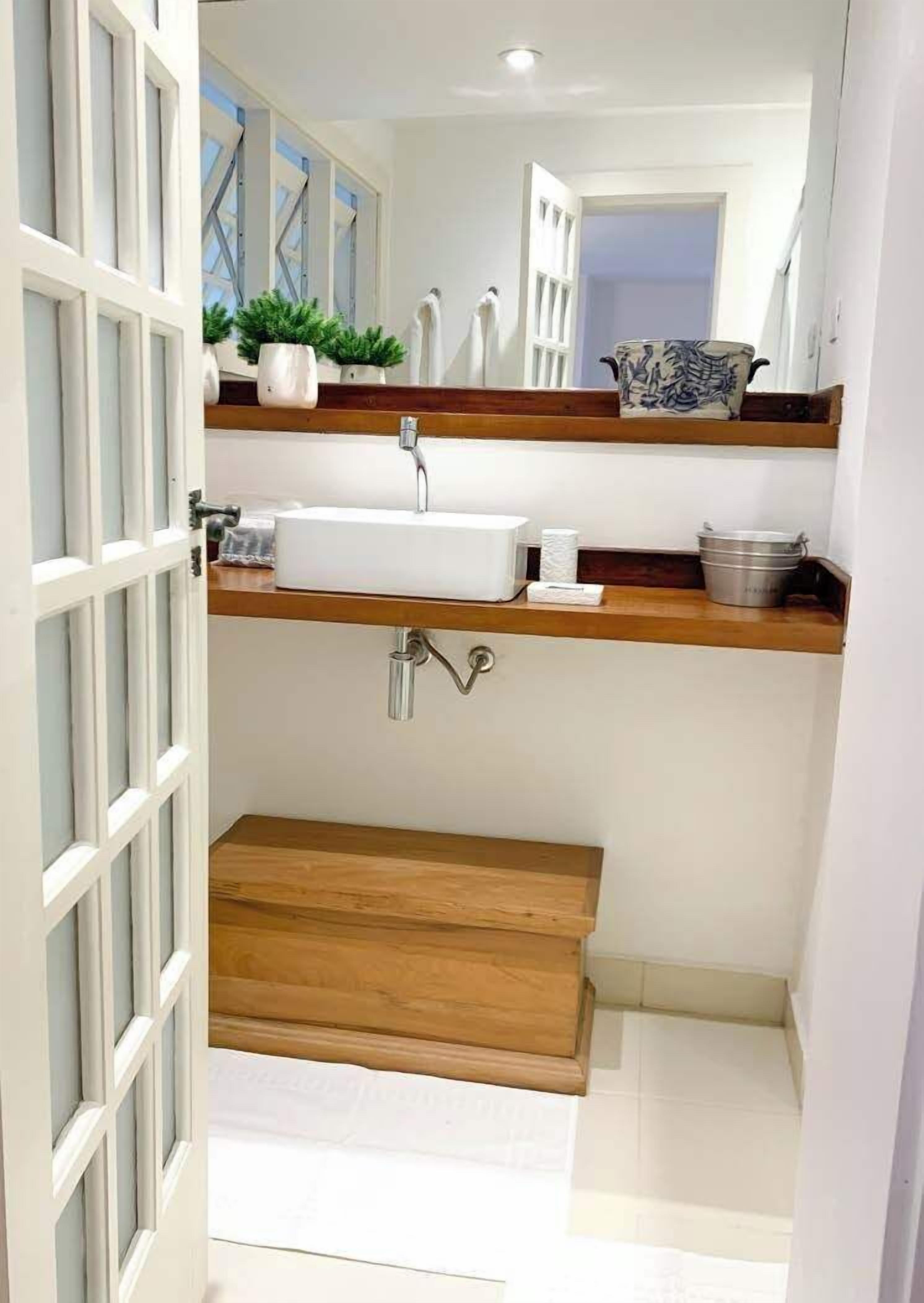 A modern bathroom with a white sink, wooden vanity, and a mirror above the sink.
