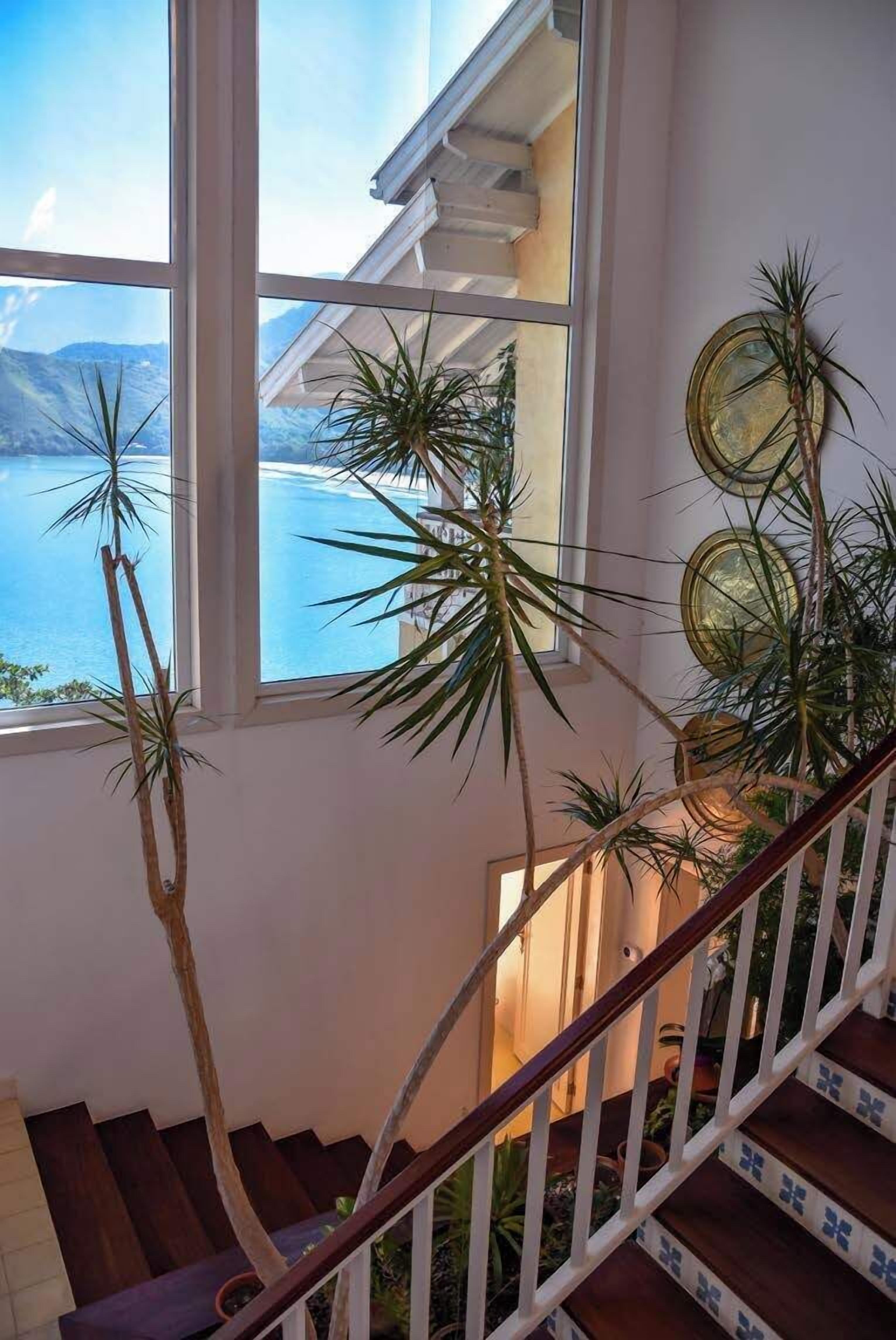 A staircase with a view of the ocean, surrounded by potted plants and decorative plates.