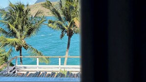 A view of a coastal area with palm trees and a mountain in the background. - Villa Dei Fiori (São Sebastião)