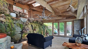 Un intérieur rustique avec un mur en pierre, un lustre suspendu, un canapé et une table en bois.