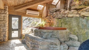 Un espace de bien-être doté d’un mur en pierre, d’un jacuzzi et de fenêtres de toit.
