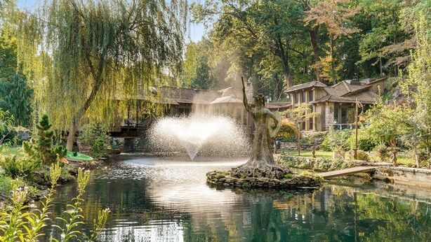 Un jardin paisible avec un étang, un pont de pierre et un bâtiment en bois au design traditionnel.