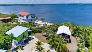 A coastal property with multiple buildings, including a large white house with a red roof and a smaller blue and green structure.