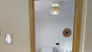 Une chambre à coucher comprenant un lit, une table de chevet avec une lampe et un élément décoratif fixé au mur.