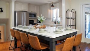 Une cuisine moderne avec des meubles blancs, des appareils en acier inoxydable et un grand îlot central doté de sièges.