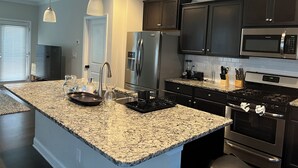 A modern kitchen with granite countertops, stainless steel appliances, and dark cabinetry. - Spacious 4-bedroom townhome with WiFi, AC in terrific Fort Mill (Fort Mill)