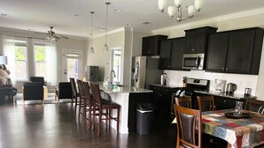 A spacious kitchen with dark wooden floors, black cabinets, and stainless steel appliances. There is a dining area with a table covered by a colorful tablecloth. - Spacious 4-bedroom townhome with WiFi, AC in terrific Fort Mill (Fort Mill)