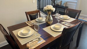 A dining table set with white plates, silverware, and a vase of white flowers. - Spacious 4-bedroom townhome with WiFi, AC in terrific Fort Mill (Fort Mill)