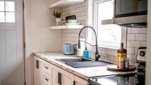 Een keuken met witte kastjes, een spoelbak, een magnetron en een fornuis.