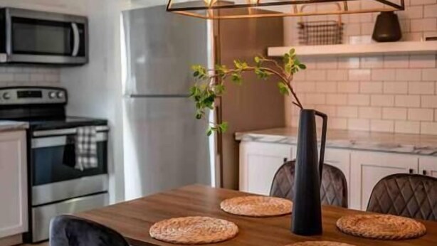Een moderne keuken met een houten tafel, een zwarte vaas met een plant en een hangende lamp.