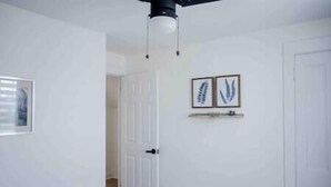 Une pièce aux murs blancs, avec une porte et deux tableaux encadrés accrochés au mur.