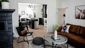 Un salon moderne avec une cheminée, un canapé en cuir marron, une table basse ronde et, au fond, un coin repas.